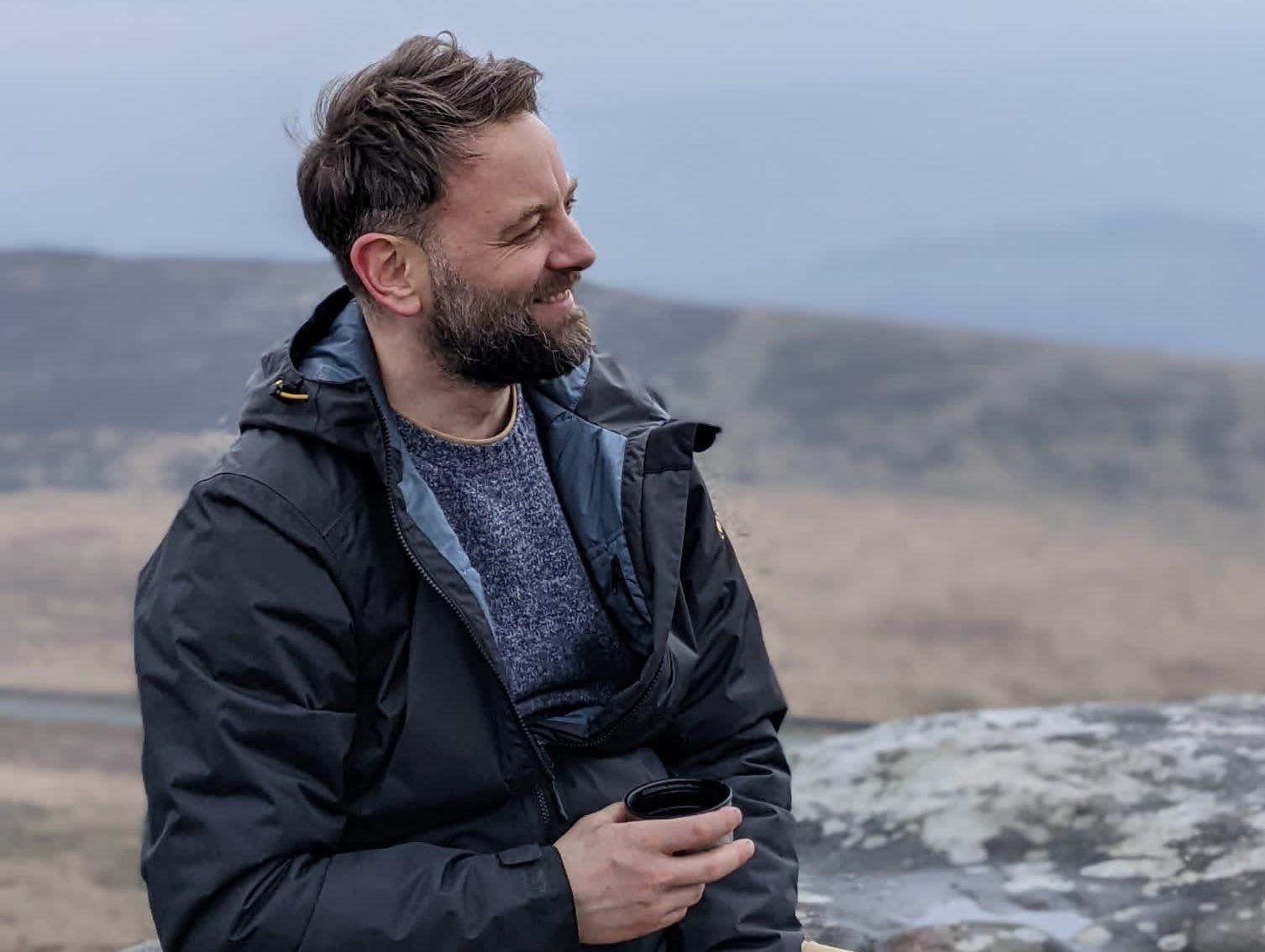 Alex Warren sits drinking tea on a rock in the Peak District