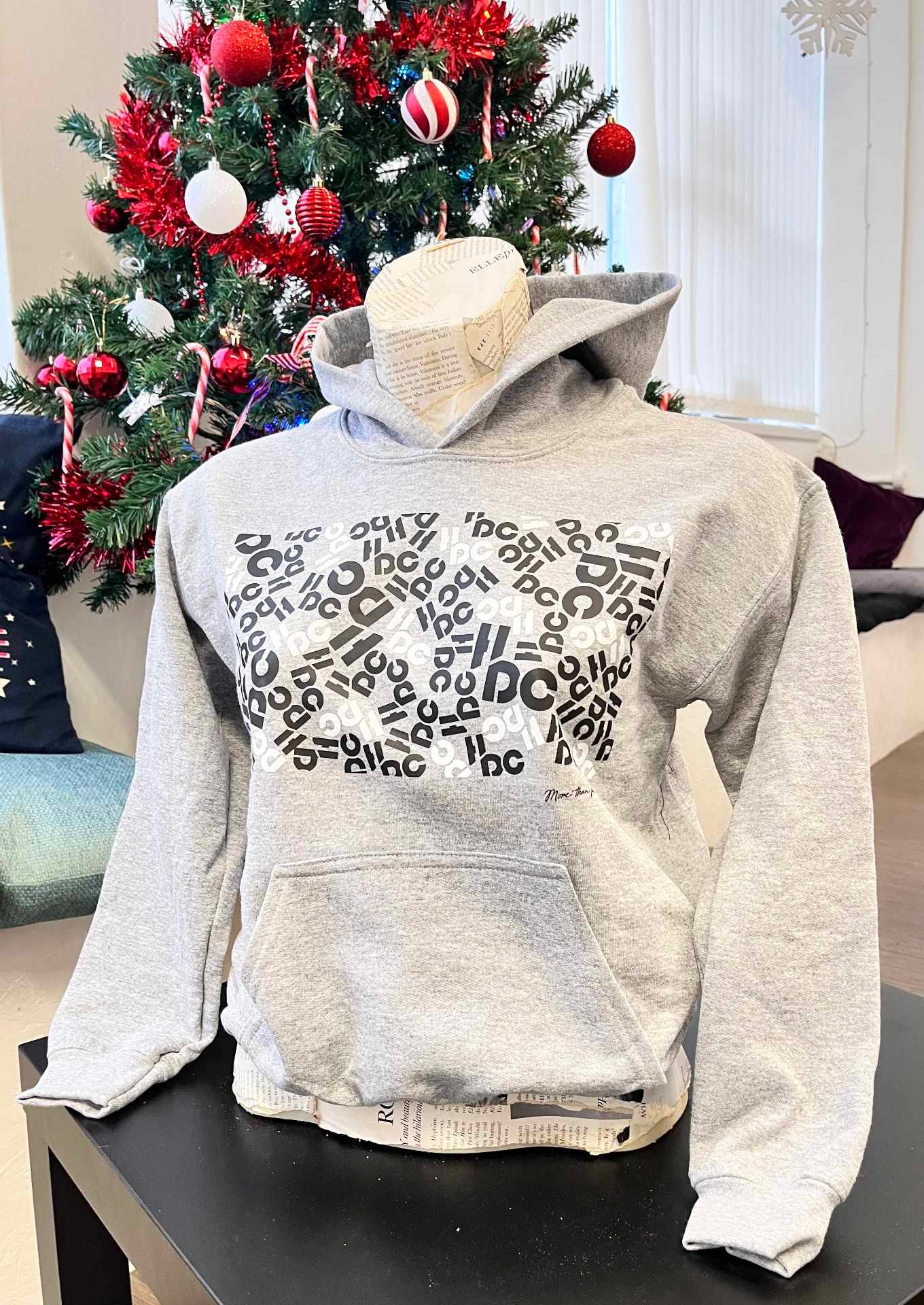 A Hype dance branded grey hoodie in front of a Christmas tree