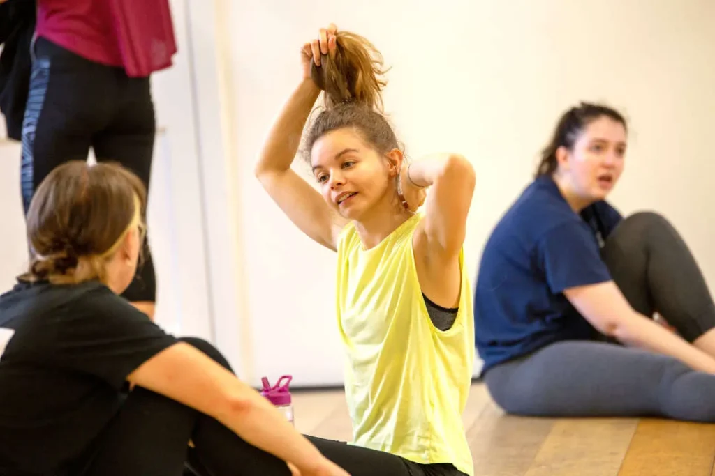 Adult dancers chatting on the studio floor between exercises at Hype Dance's Sheffield studio