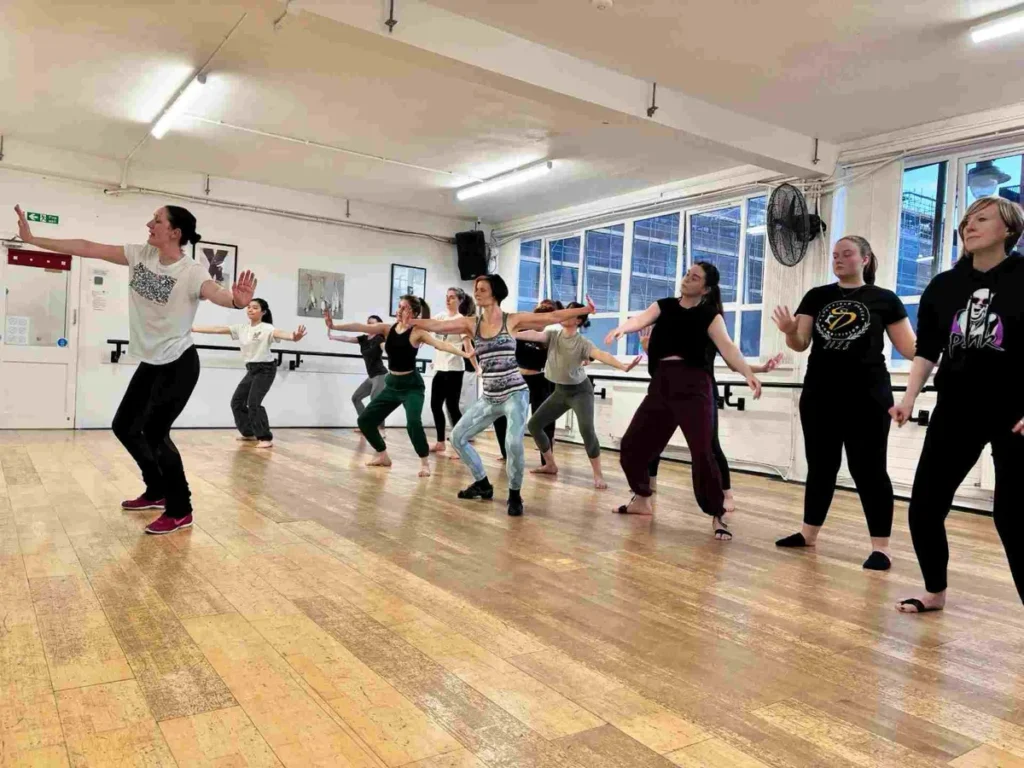 Adults dancing together in a modern jazz class at Hype Dance's Sheffield studio, stepping forward with their arms stretched out